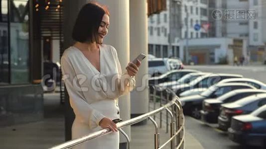 美丽优雅的商务女性步行通过城市连接使用智能手机。 穿白色衬衫的快乐女士视频