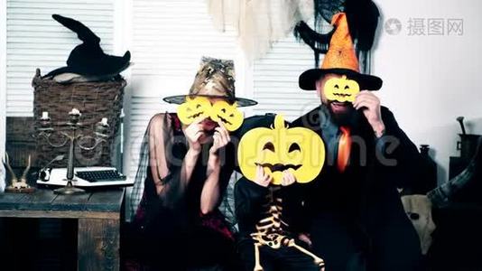 万圣节派对和庆祝理念。 巫师，女巫和小骨架把他们的脸藏在南瓜后面。 家庭视频