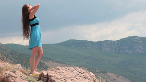 一个年轻的女人站在海边的岩石上18秒视频