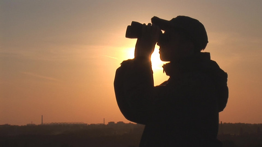 年轻人在日落时透过望远镜看剪影视频