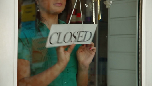 店主在她的商店前把标志从打开变成关闭视频