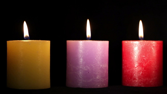 黄色紫色和红色蜡烛隔离在黑色上视频