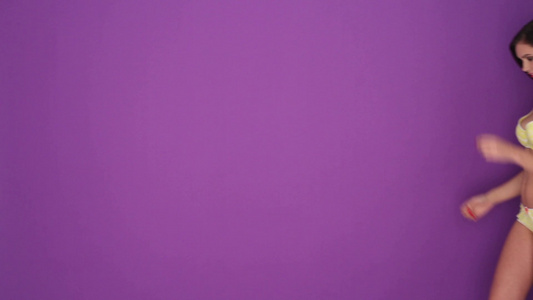 穿着黄色内衣的性感年轻女人的肖像被隔离在紫色的背景上视频