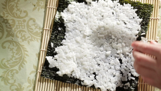 把米饭放在诺丽身上。 做寿司卷。 高角度视图。视频