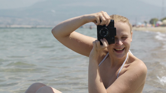 海边穿着比基尼的女生使用相机拍照视频