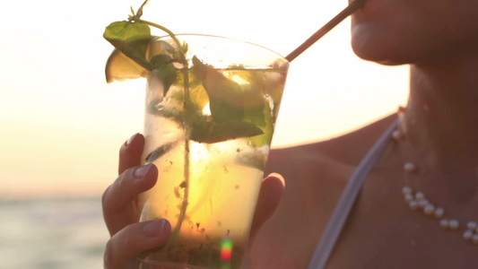 女人在沙滩边喝热带莫吉托鸡尾酒视频