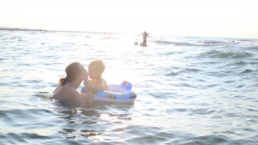 母亲带着孩子在海里游泳视频