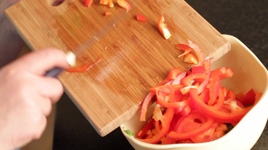 女人将砧板上切碎的红色辣椒放进碗里视频