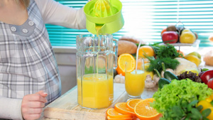 女性手在榨汁机上挤压橙汁13秒视频