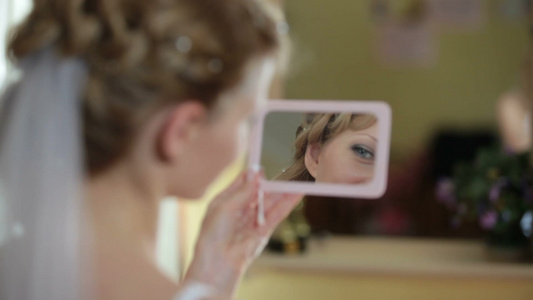 新娘拿着镜子看着自己化妆后美丽的脸视频