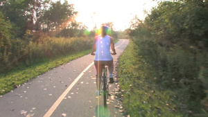 一个年轻的女人骑着自行车在一条草原小路上穿过森林15秒视频