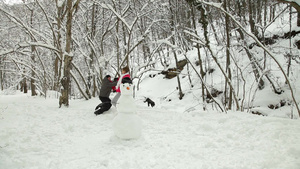 冬天雪地里堆雪人的青年夫妇26秒视频