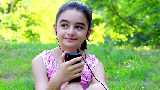 小女孩在公园里听音乐视频