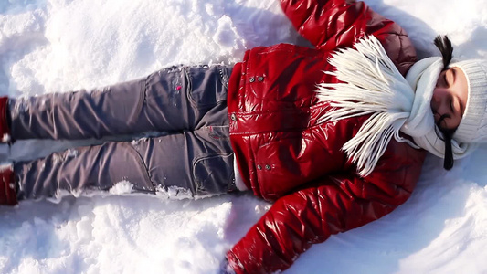 可爱的女孩躺在雪地里玩耍视频