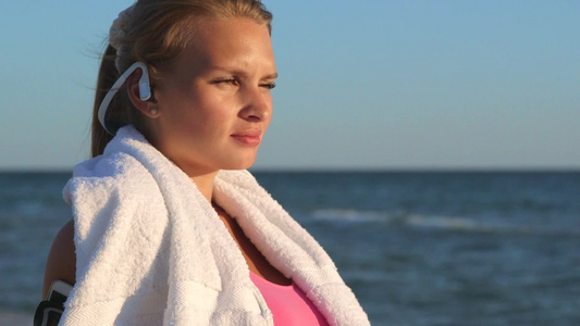 健身女孩放松听音乐面对着海滩视频
