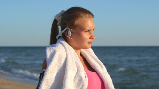 在海滩上带着耳机锻炼的女孩视频