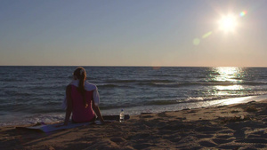 夕阳下健身女性坐在沙滩上休息16秒视频