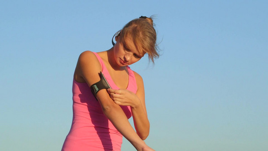 健身年轻妇女触摸手机屏幕在户外锻炼视频