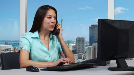 年轻的商业妇女在电脑前工作接电话提供专业咨询服务视频