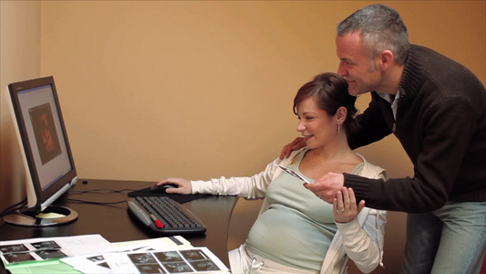 孕妇和她的丈夫在看他们孩子的超声波照片视频