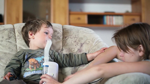 母亲帮助生病的小男孩用喷雾器吸入药物27秒视频