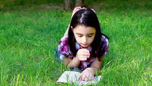 小女孩在公园草地上看书27秒视频