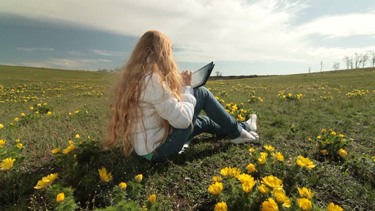 坐在草地上玩平板电脑的女孩视频