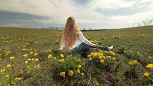 金发女孩坐在开着黄色牡丹的草地上20秒视频