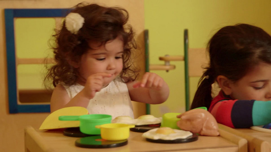 幼儿园里小女孩们用仿真塑料玩具在玩模仿大人厨房做饭的游戏视频