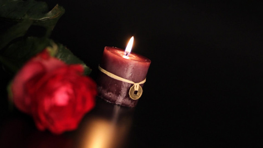 黑色背景上的红玫瑰和蜡烛。视频