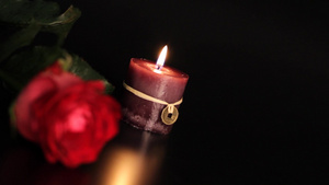 黑色背景上的红玫瑰和蜡烛。14秒视频