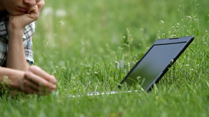 躺在绿草地上的青少年在使用笔记本电脑15秒视频