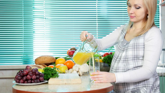 孕妇在厨房里倒橙汁视频