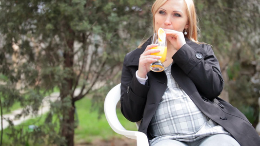 孕妇在户外坐着喝橙汁视频