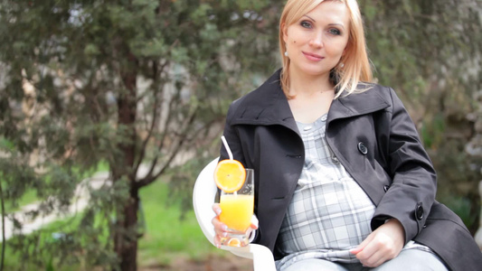 孕妇在户外坐着喝橙汁视频