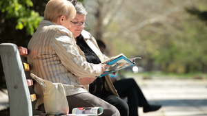老年女性朋友在城市公园读的杂志27秒视频