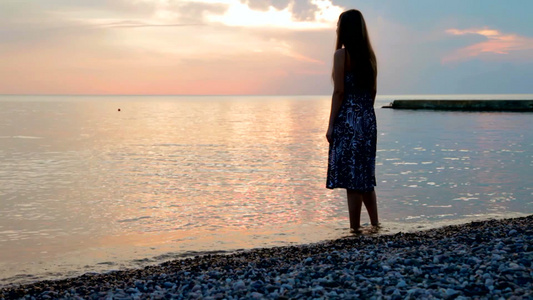 年轻的女人在海边的海滩上看日落[二十多岁]视频