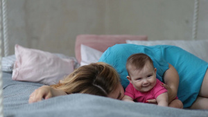 深情的年轻母亲早上躺在床上亲吻她的小宝宝21秒视频