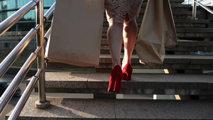 提着购物袋穿着红色高跟鞋的纤细女性腿在楼梯上行走的特写14秒视频