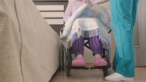 年轻护士照顾轮椅上的老年残疾妇女转移到床上29秒视频