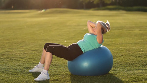 美丽的成年女性在适合的球上做腹部仰卧起坐20秒视频