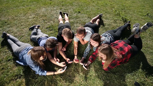 一群青少年躺在草地上看手机15秒视频