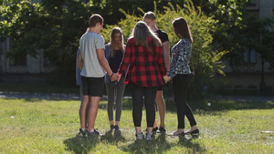 一群大学生手拉手站在绿草地16秒视频