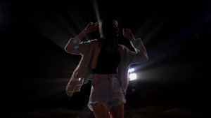 在夜间城市街道汽车前灯下自由热舞的美丽女人37秒视频