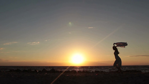 日落时在海滩举起飞扬的丝巾奔跑的女孩剪影17秒视频