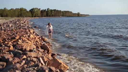 夏季年轻女性在海边沙滩散步蹚水吹风视频