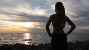 自信的运动苗条的女人站在岩石海岸享受海景27秒视频