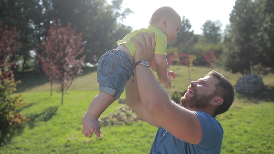 年轻在公园男子将婴儿举起来视频