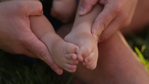 特写深情的父亲手里拥抱着抚摸着小婴儿的脚9秒视频