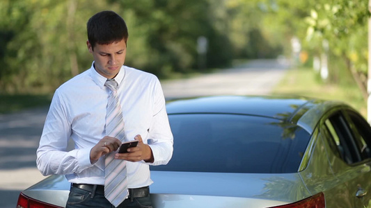 在户外用手机浏览网络倚靠在汽车旁的商务人士视频